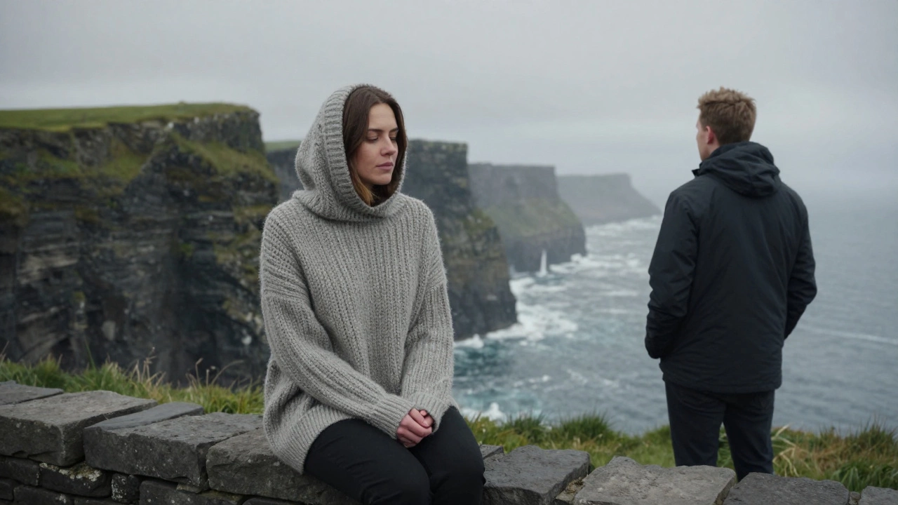 A woman wrapped in a woolen Aran sweater sits on a cliff edge, gazing at stormy seas with quiet calm.