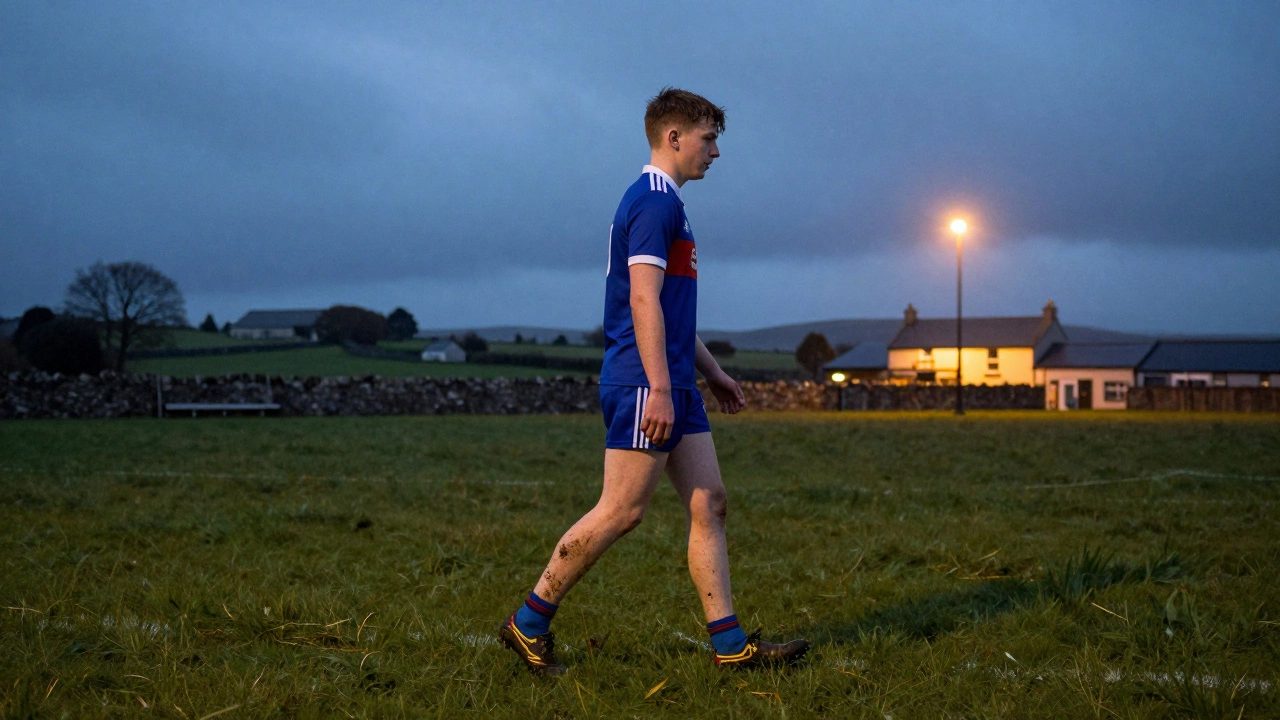 A young GAA player walking home from a match in muddy trainers across a rural Irish field at twilight.